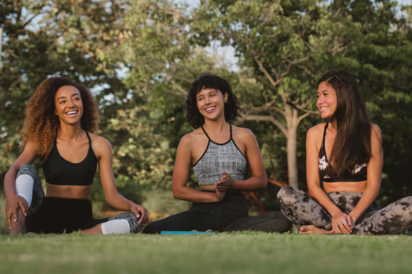 Three women doing yoga in park