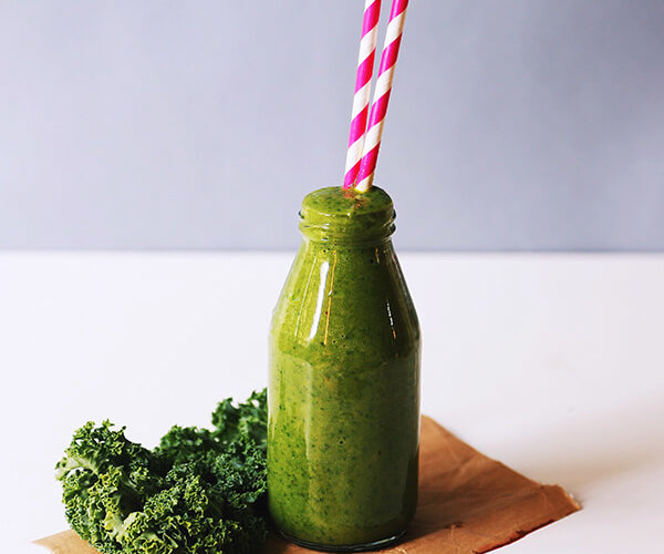 Green smoothie in Glass jar with pink and white striped straw