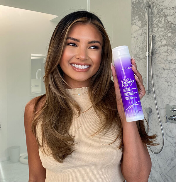Woman smiling holding Joico color balance Purple shampoo